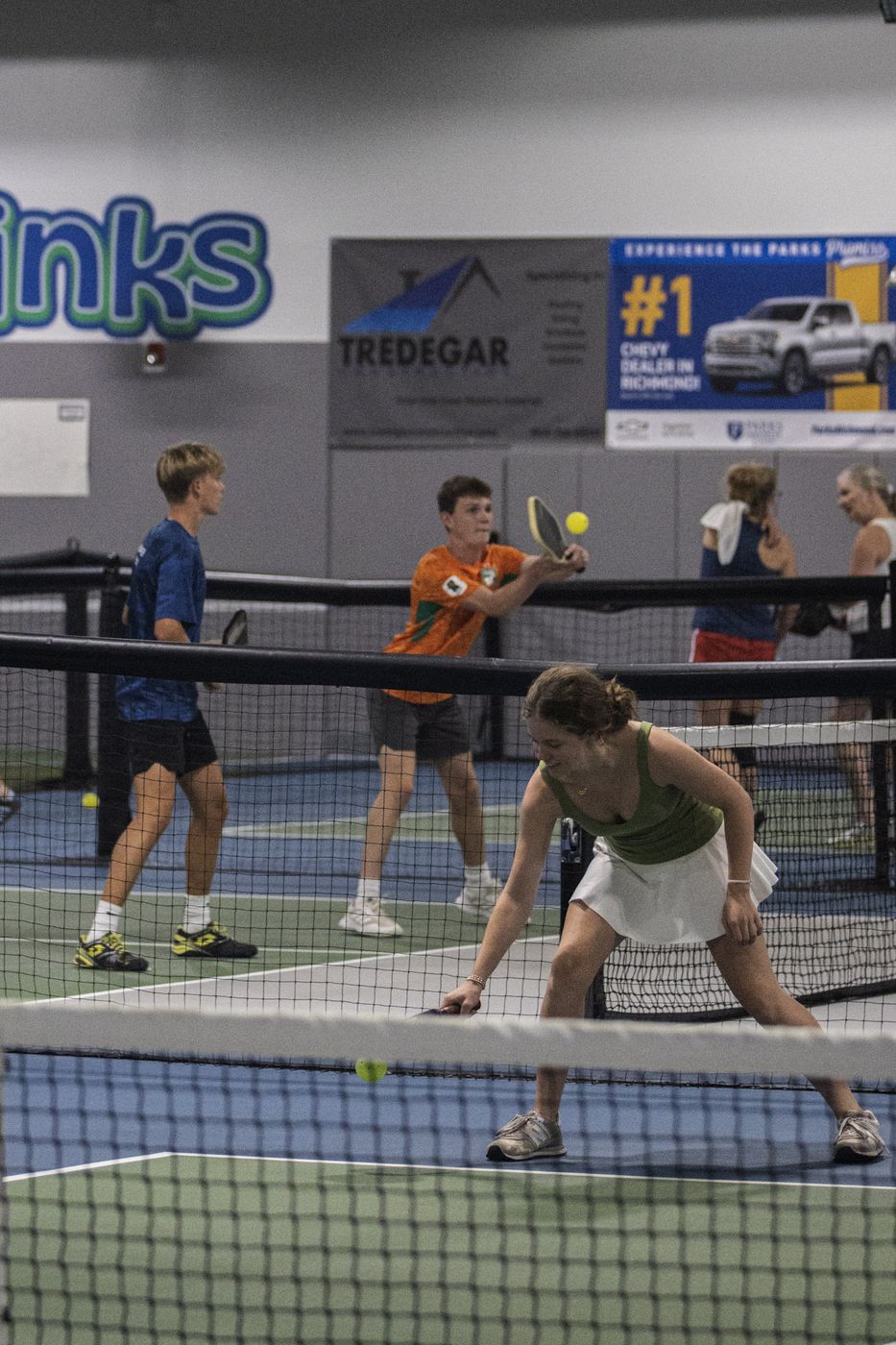 Player crouching low for a dink during a doubles game