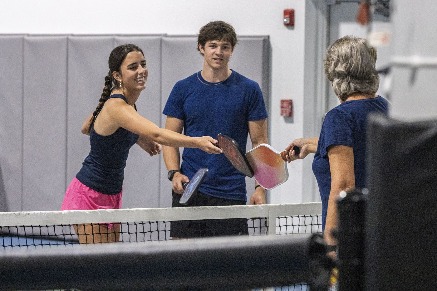 Players tapping paddles at the net after a game